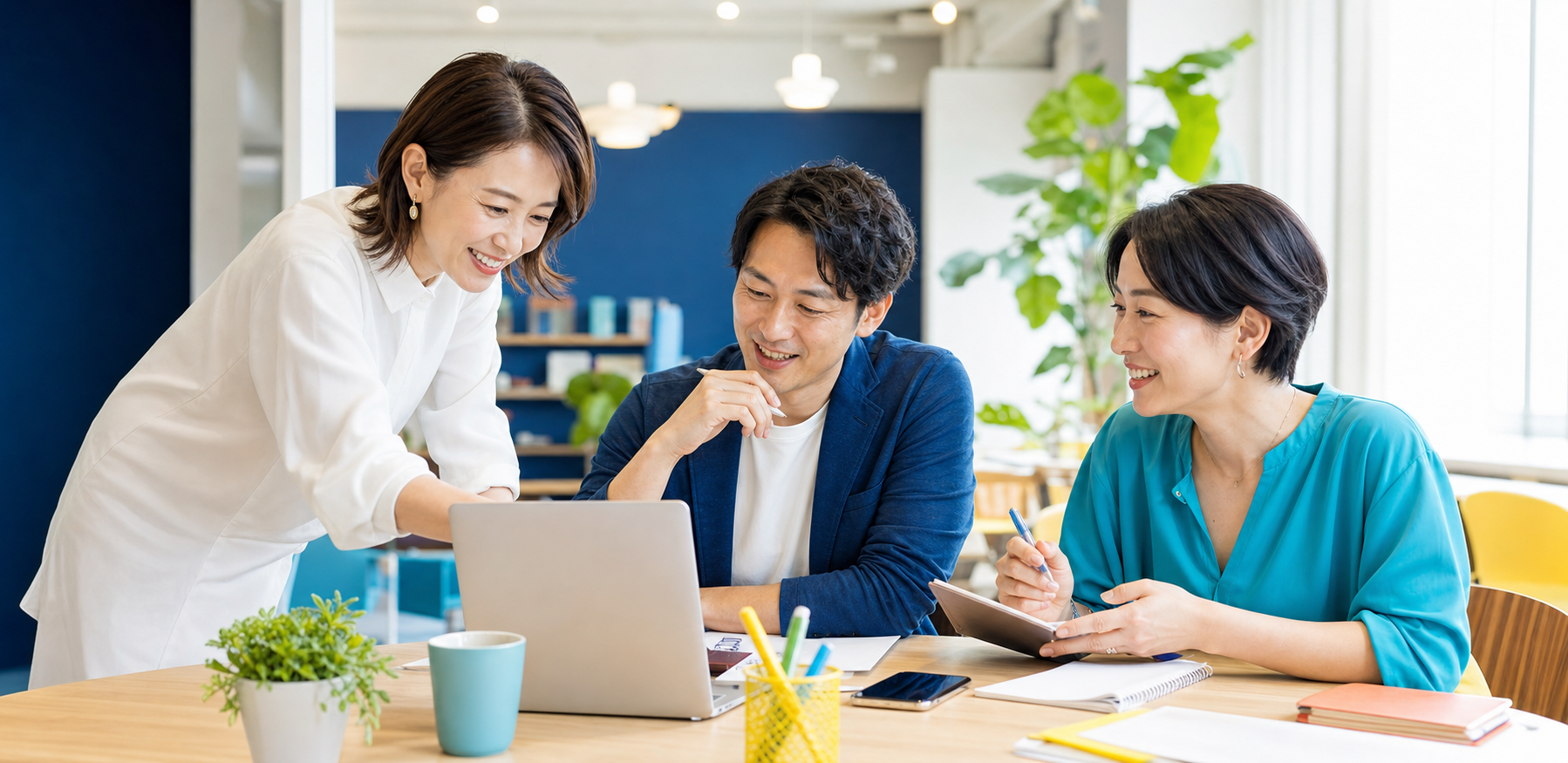 30代から40代の男女が明るい教室でパソコンを囲んで学ぶ様子